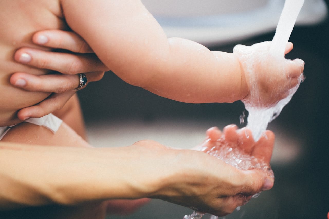 who-we-are Heartwarming close-up of a parent gently washing a baby's hand under running water.