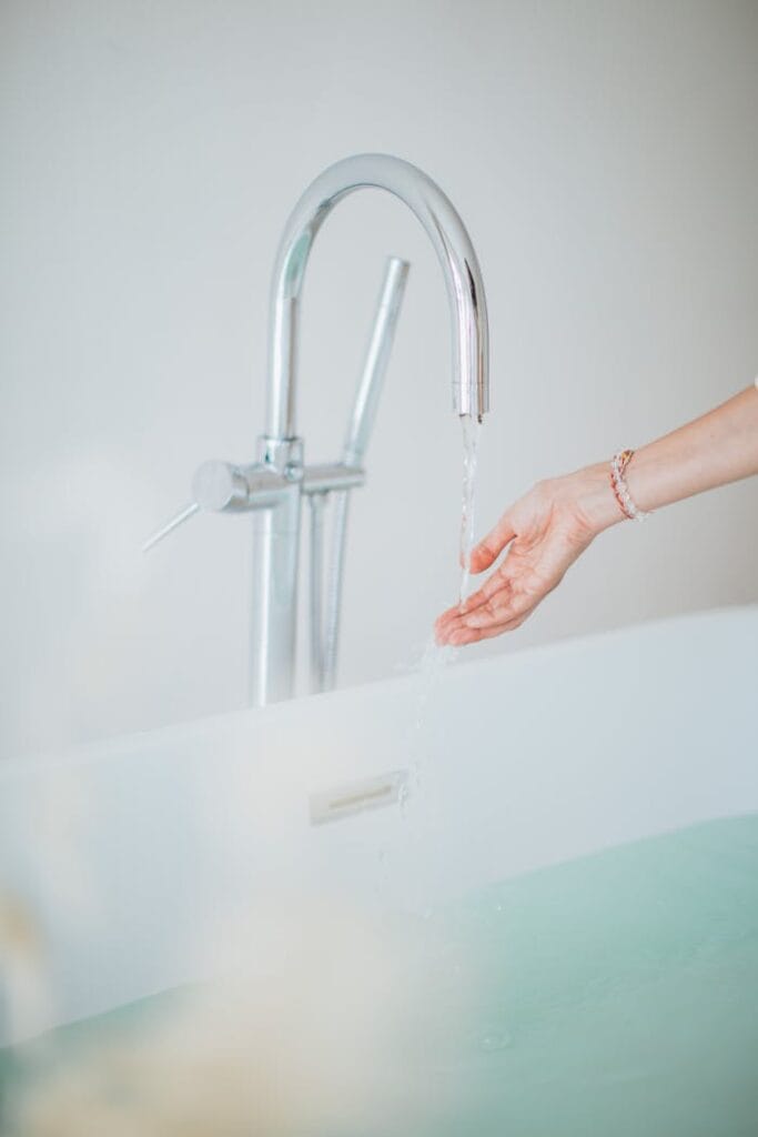 pexels photo 3865696 A woman's hand checks the flowing water temperature in an elegant bathtub.